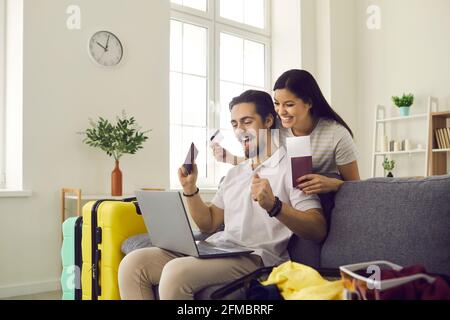 Felice coppia che si prepara per il viaggio di vacanza e utilizzando il computer portatile per prenotare i biglietti online Foto Stock