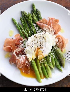 Uova Benedetto con parmigiano, asparagi verdi e prosciutto di Parma Foto Stock