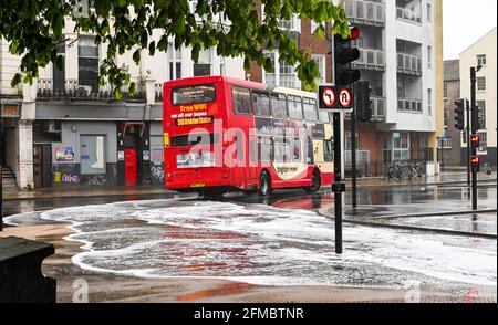 Brighton UK 8 maggio 2021 - UN autobus passa attraverso le acque alluvionali sulle strade intorno alla zona Valley Gardens di Brighton, come pioggia pesante passa attraverso la maggior parte delle parti della Gran Bretagna oggi, ma si prevede di riscaldarsi da domani nel Sud-Est : Credit Simon Dack / Alamy Live News Foto Stock
