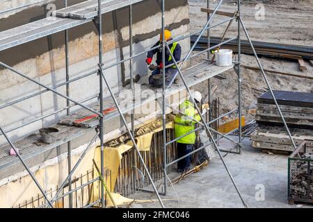 Costruttore con cazzuola intonacatura parete di cemento in cantiere. Foto Stock