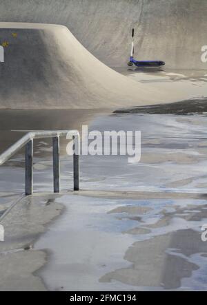 Abbandonato Blue Stunt Scooter in UN bagnato, vuoto Skate Park durante il Coronavirus Lockdown in UNA giornata piovosa. Christchurch Regno Unito Foto Stock