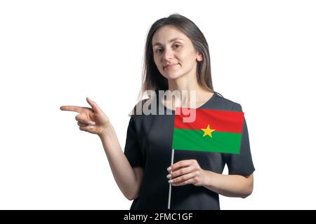 Felice giovane donna bianca che tiene bandiera Burkina Faso e punta a sinistra isolata su uno sfondo bianco. Foto Stock