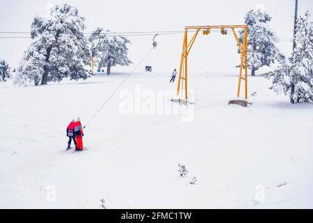 Bambini che usano lo skilift di superficie in salita, attività all'aperto. Sport invernali e turismo sciistico. Foto Stock