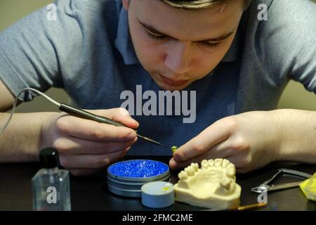 Tecnico dentale modellando le corone dei denti con cera calda. Luogo di lavoro di un tecnico odontoiatrico Foto Stock