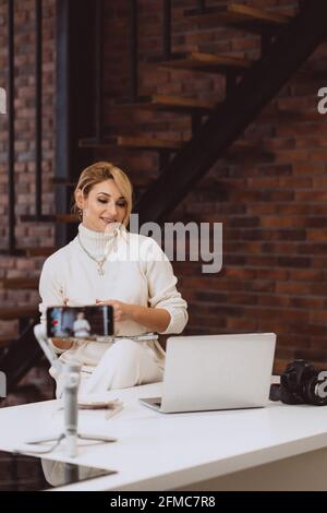 Il concetto di blogging e vlogging è una giovane blogger donna che parla con la macchina fotografica. Messa a fuoco selettiva, sfocatura, disturbo artistico. Foto Stock