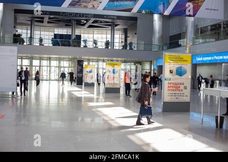 Mosca, Russia - 14 aprile 2021 : la gente cammina nella hall del centro espositivo Crocus Expo di fronte all'ingresso della mostra Foto Stock