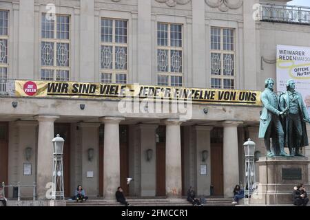 Weimar, Germania. 8 maggio 2021. "NOI SIAMO MOLTI - OGNI SINGOLO degli Stati Uniti" è scritto al Teatro Nazionale Tedesco di fronte al Goethe-Schiller Monument. Con il motto "Oro anziché marrone", varie associazioni, sindacati e iniziative della Turingia hanno richiesto azioni speciali in occasione dell'anniversario della liberazione dal nazionalsocialismo l'8 maggio 2021. Credit: Bodo Schackow/dpa-Zentralbild/dpa/Alamy Live News Foto Stock