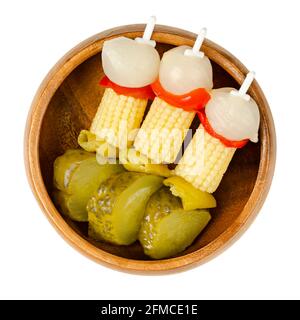 Spiedini di verdure in una ciotola di legno. Verdure decapate su spiedini di plastica. Cipolle perlate, peperoni rossi, mais, peperoncini verdi e cetriolini Foto Stock