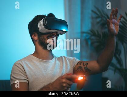 Giovane uomo che gioca a videogiochi online con occhiali di realtà virtuale A casa - giovani dipendenti di nuove tecnologie di gioco intrattenimento Foto Stock