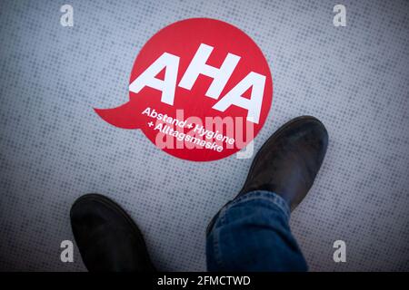 28 aprile 2021, Meclemburgo-Pomerania occidentale, Greifswald: Di fronte al locale di lavoro dei traccianti di contatto nell'ufficio distrettuale di Vorpommern-Greifswald, è appiccato sul pavimento un avviso per il rispetto delle regole di distanza. La centrale telefonica discute l'ulteriore procedura con i cittadini che devono rimanere in quarantena a causa delle misure di protezione di Corona. Foto: Jens Büttner/dpa-Zentralbild/dpa Foto Stock