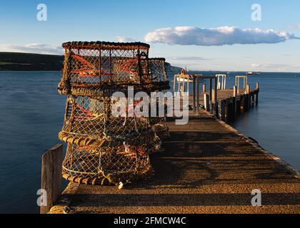 Pentole di aragosta su un molo di legno al tramonto a Swanage, Dorset, Regno Unito Foto Stock