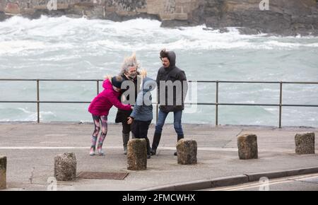 Cornovaglia, Regno Unito. 8 maggio 2021. Una famiglia di quattro persone si trova accanto alla parete del mare nonostante i venti estremamente forti di Porthleven, Cornovaglia. La temperatura era di 12C, la previsione è per pioggia e forti venti nei prossimi giorni. Credit: Keith Larby/Alamy Live News Foto Stock