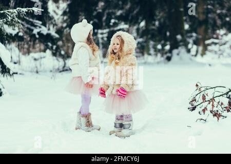 due bambine in pelliccia giocano in inverno foresta Foto Stock