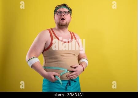 il concetto di uno stile di vita sano. L'uomo sovrappeso misura i parametri del corpo Foto Stock