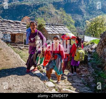 Felici donne e bambini sorridenti che salgono lungo il ripido sentiero Al villaggio di Supi nel Uttarakhand Himalaya di India del Nord Foto Stock