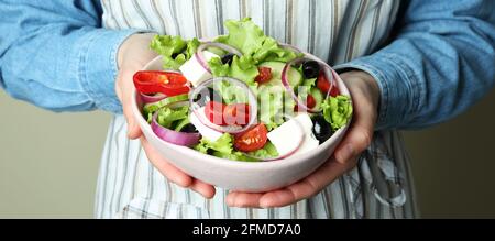 Donna in grembiule contiene ciotola di insalata greca Foto Stock