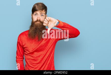 Uomo a testa rossa con barba lunga e vestiti casual che non è felice e arrabbiato mostrando rifiuto e negativo con i pollici verso il basso gesto. Cattiva espressione. Foto Stock