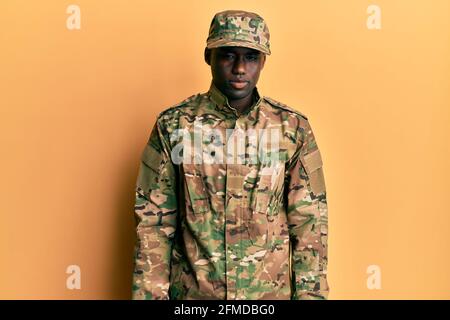 Giovane afroamericano uomo che indossa uniforme esercito che guarda sonnolento e stanco, sfinito per stanchezza e sbornia, occhi pigri al mattino. Foto Stock