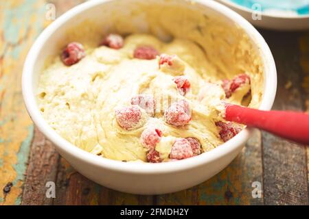 Preparazione di avocado, torta di lime con frutti di bosco. Impastare con lamponi in una ciotola con cucchiaio. Foto Stock