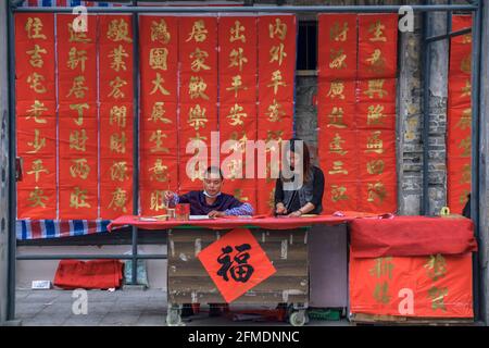 Foshan, provincia di Guangdong, Cina. 8 FEBBRAIO 2021. Un calligrafo sta scrivendo i couplets di festa della molla per la gente. È il cus più comune e importante Foto Stock