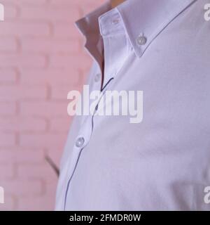 maglia bianca da uomo da vicino contro la parete bianca in mattoni. Foto Stock