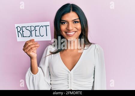 Giovane latino transessuale transgender donna tenendo rispettare messaggio carta cercando positivo e felice in piedi e sorridente con un sorriso fiducioso visualizzazione Foto Stock