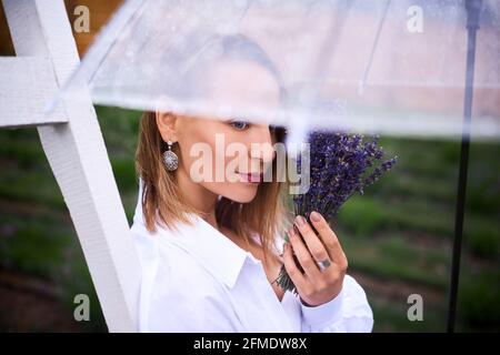 ritratto di bella donna con un orecchio insolito sotto ombrello trasparente. profondità di campo poco profonda foto Foto Stock