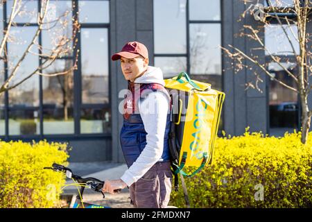 KIEV, UCRAINA - 28 aprile 2021: Glovo bike Courier sulla strada. Consegna ragazzo di Glovo servizio di consegna Foto Stock