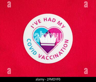 Londra, UK - 25 aprile 2021: Primo piano di un adesivo di vaccinazione di Ive Had My Covid attaccato su un materiale rosso. Foto Stock