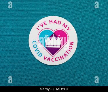 Londra, UK - 25 Aprile 2021: Primo piano di un adesivo di vaccinazione di Ive Had My Covid attaccato su un materiale colorato di teal. Foto Stock