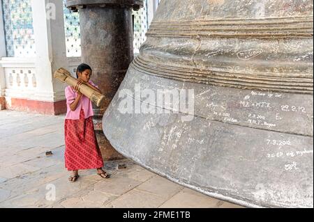 Giovane ragazza che stringe la grande Campana di Mingun. Mingun, Regione di Sagaing, Myanmar. Foto Stock