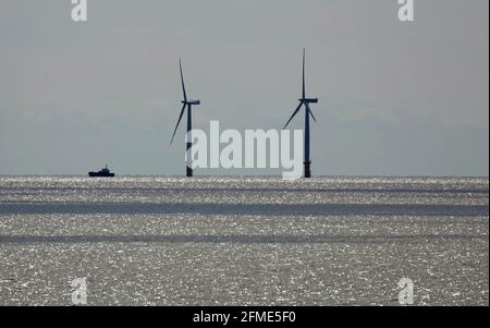 Svuotare il mare con un paio di turbine eoliche nel acqua e una barca soleggiato che naviga accanto a loro Foto Stock