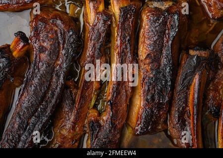 Costolette di maiale alla griglia con rosmarino e miele, in padella di ghisa, su fondo di pietra nera, vista dall'alto piatto Foto Stock