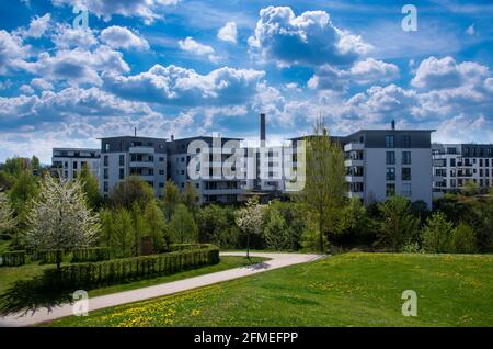 Moderni edifici di appartamenti con prato primaverile in primo piano e. cielo nuvoloso di primavera Foto Stock