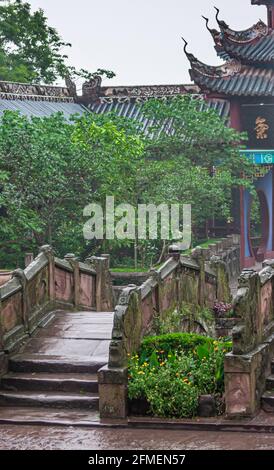 Fengdu, Cina - 8 maggio 2010: Città fantasma, santuario storico. Superfici piovose bagnate di pietra del ponte che conduce alle strutture del tetto di Pagoda intorno in combinazione con Foto Stock