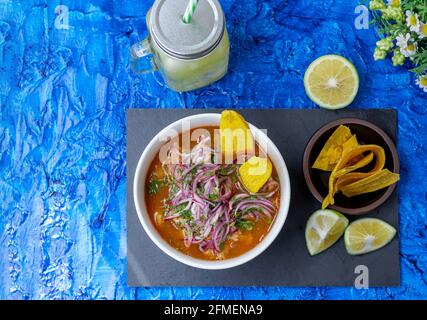 Vista dall'alto di un encobollado, un cibo tipico dell'Ecuador preparato con pesce, cipolla, limone e yucca su sfondo blu. In Ecuador è di solito mangiato Foto Stock