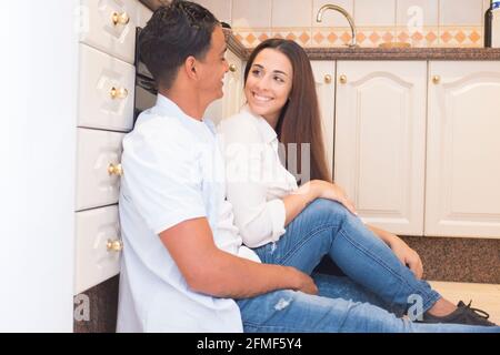 Felice giovane coppia godere di nuovo appartamento casa insieme seduta sopra il pavimento in cucina - amore e vita persone concetto con l'uomo allegro e la donna lo Foto Stock