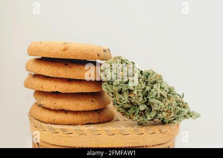Dolci con olio CBD. Gemme di marijuana su sfondo bianco. Primo piano fiori di cannabis e biscotti al cioccolato. Foto Stock