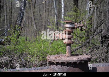 Un idrante su una conduttura industriale di approvvigionamento idrico sullo sfondo di una foresta di primavera. Sfondo. Foto Stock