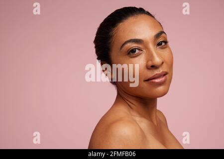 Ritratto di una donna di razza mista con bella pelle. Modello femminile fissando la fotocamera su sfondo rosa. Foto Stock