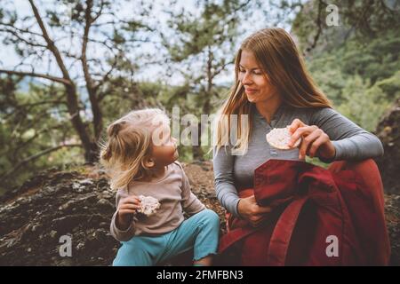 Famiglia stile di vita madre e figlia bambino all'aperto nella foresta picnic mangiare biscotti di riso viaggio vacanze insieme con il bambino Foto Stock