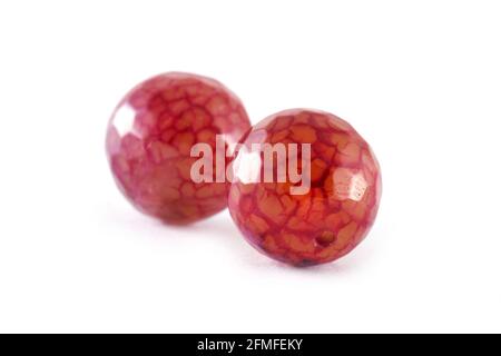 Perline di agata rossa cremisi a motivi decorati isolate su perline bianche, tonde di Agata, pietre semi preziose. Perle minerali naturali. Perle fatte di pietre naturali a cre Foto Stock