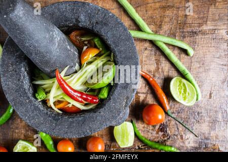 Cucina thailandese, insalata di papaya e condimento su un tavolo di legno Foto Stock