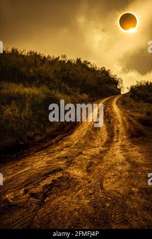 Incredibile fenomeno scientifico naturale. La Luna che copre il sole totale eclissi solare con effetto anello diamante che illumina sul cielo sopra strada fangosa attraverso Foto Stock