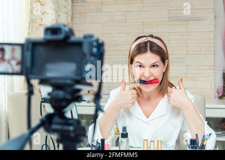 Bella donna di mezza età blogger mostra come utilizzare i cosmetici. Registrazione live di blog video a casa. La versione moderna del lavoro a casa. Foto Stock