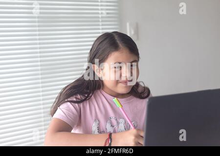 Una ragazza ispanica colombiana che lavora al suo progetto scolastico a casa, la nuova normalità Foto Stock