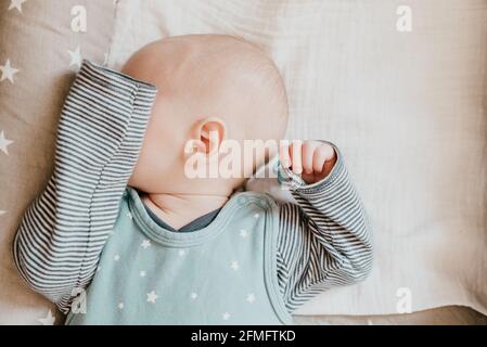 primo piano del bambino addormentato che gli copre gli occhi braccio Foto Stock
