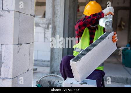 muratore per muratori in autoclave aerato con blocchi adesivi in calcestruzzo intonaco. Walling, installazione di mattoni a costruzione di casa incompiuta, Engi Foto Stock