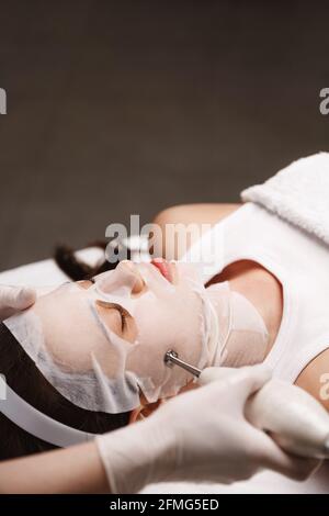 Hardware cosmetologia e concetto di salone termale. Medico di clinica di bellezza che usa il trattamento del viso di fonoforesi ultrasonica su cliente della donna. Beautician fare Foto Stock