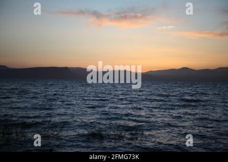 Tramonto sul mare di Galilea, le colline della bassa Galilea si vedono dall'altro lato e le nuvole sono nel suggestivo cielo colorato sopra Foto Stock